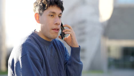 young latino man talking on smartphone outdoors