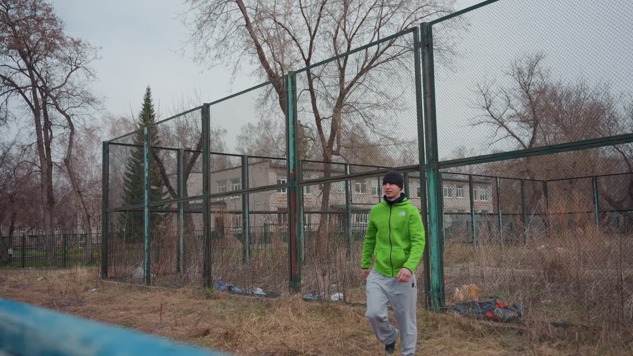 sesión de ejercicios en un parque invernal, atleta individual practicando movimientos de calentamiento al aire libre, entusiasta del fitness realizando ejercicios de calentamiento con ayuda para esgrima en un espacio urbano vacío durante el invierno
