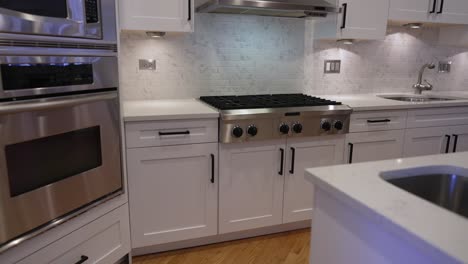 modern white kitchen interior with large island and stain steel appliances