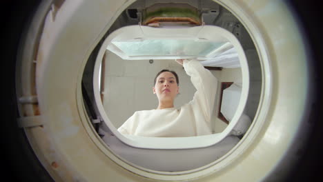woman opens the lid and looking inside the washing machine
