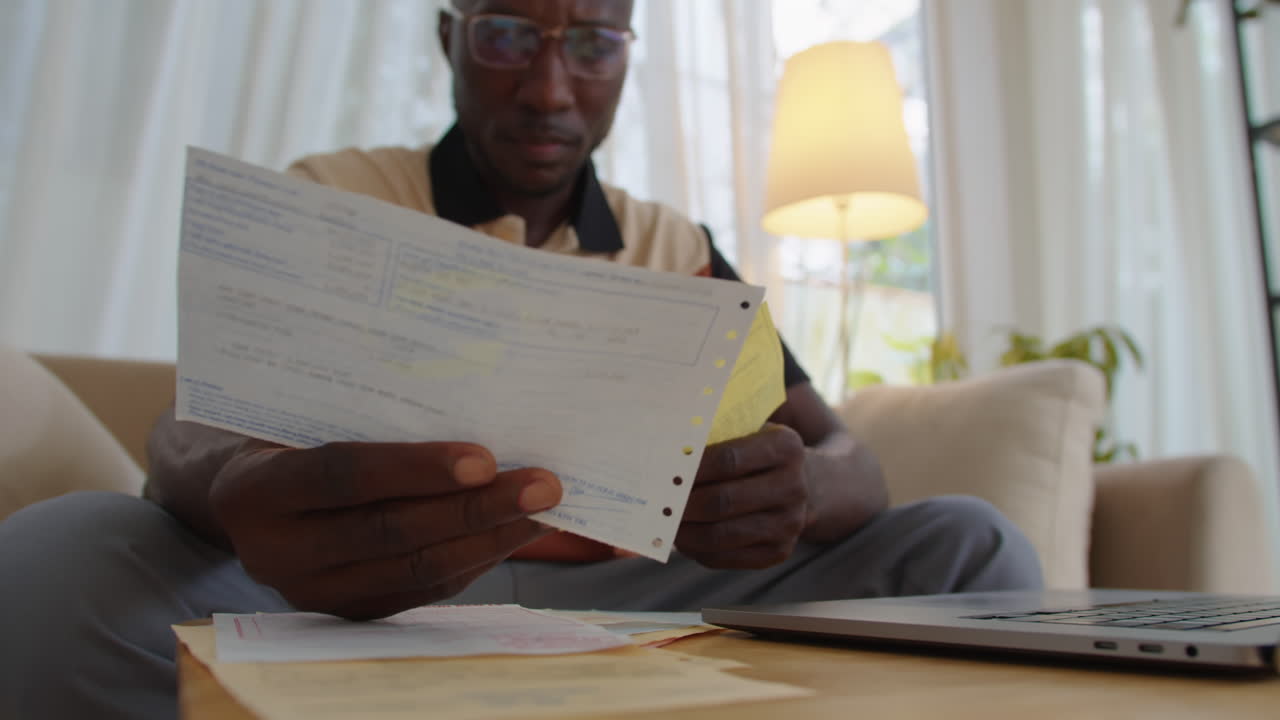 Man Looking at Bills when Paying Online from Home