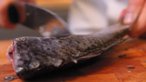 the cook is scratching fish on a wooden board