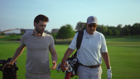 handsome golf players talk sport hobby. active men carry golfing putters clubs.