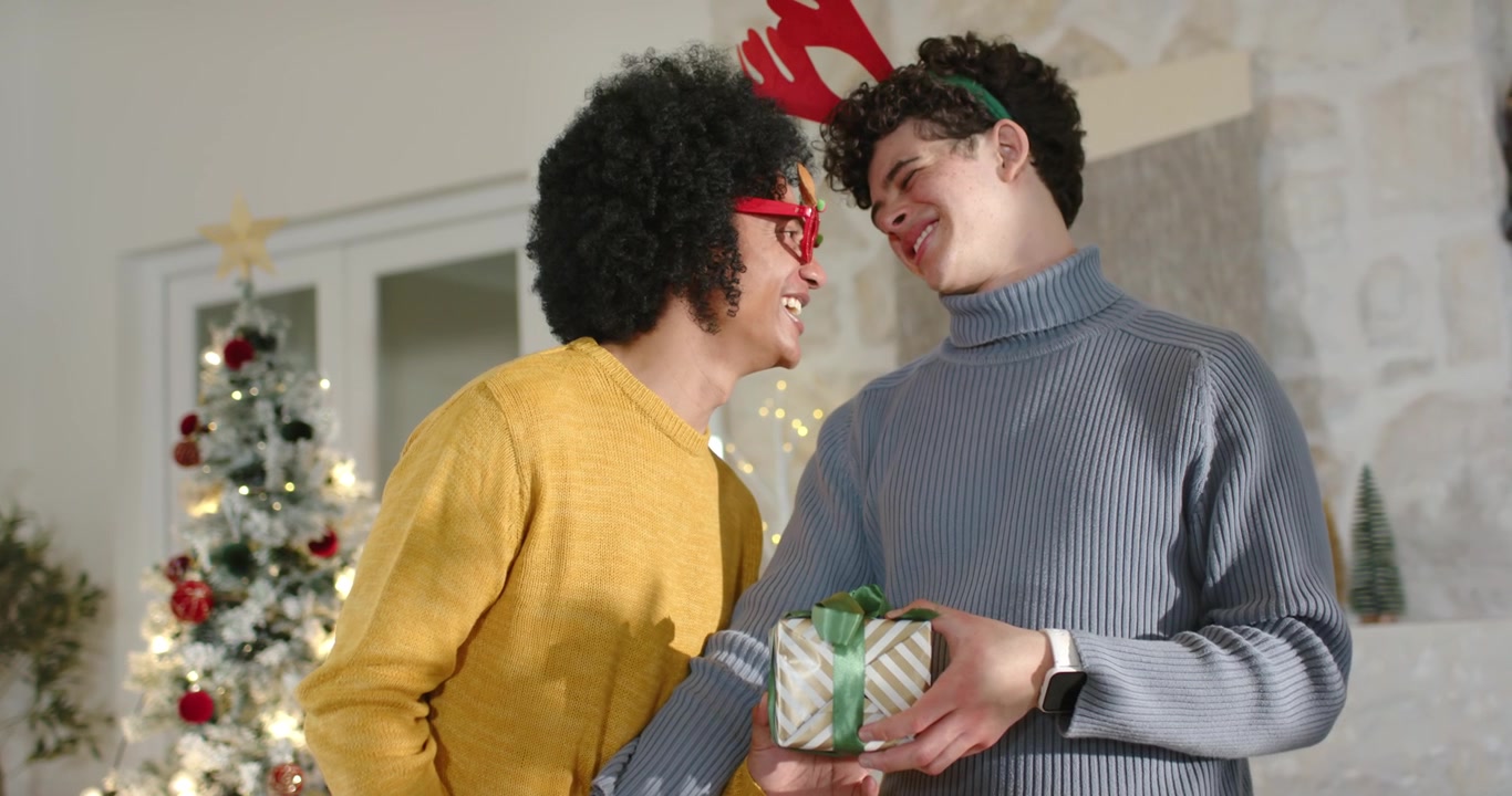 Uomini afroamericani che si scambiano regali di festa, l'uomo a destra offre una scatola, quello a sinistra tiene un regalo verde.