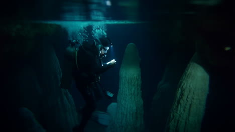 scuba diver explores dark underwater cave formations