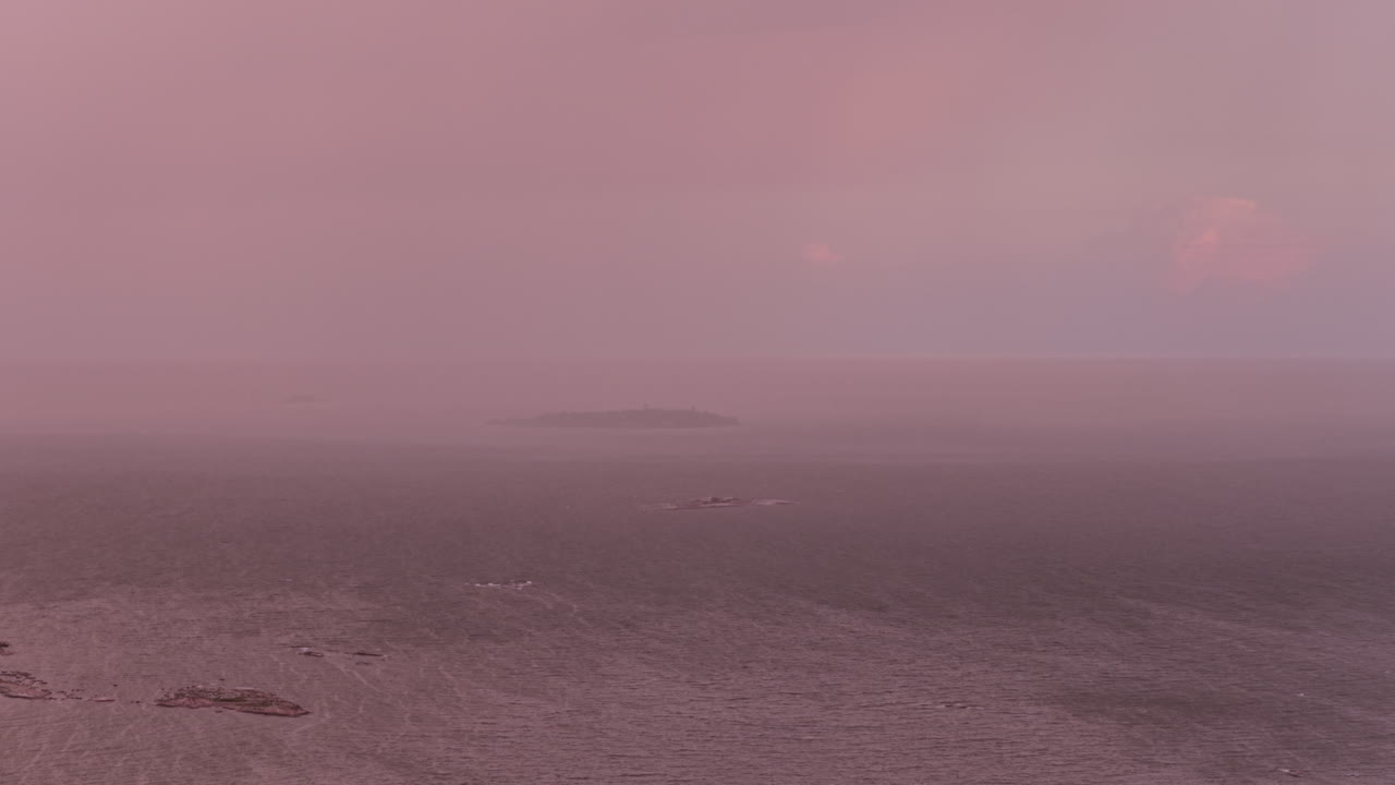 Telephoto aerial of a rain pouring over an island on the Gulf of Finland, dusk