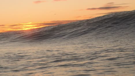 a short heavy wave crash over the shallow rock ledge as the sun rises in the background