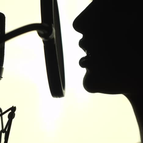 silhouette of a woman singing a song in a recording studio. black and white.
