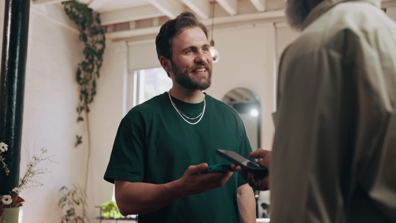 Smiling Man Interacting with Another Person While Holding a Smartphone