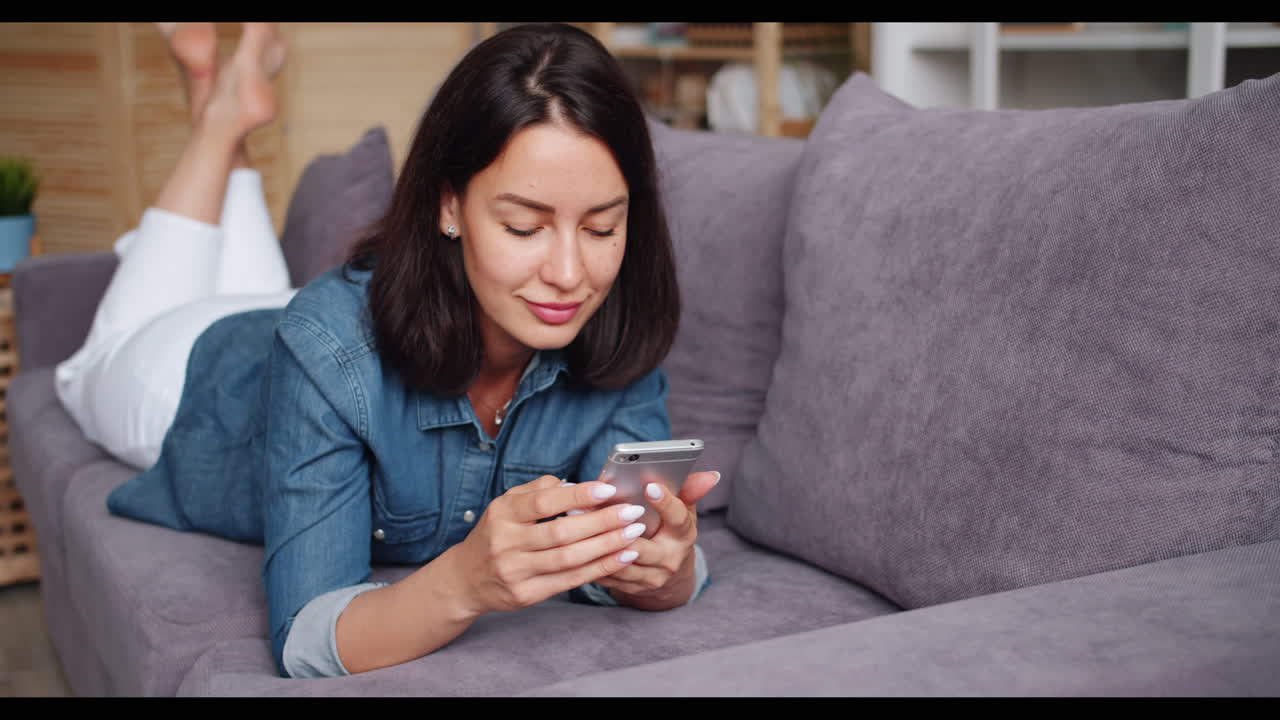 mujer relajándose en el sofá usando un teléfono inteligente
