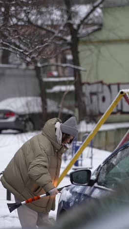 woman removing snow from a car in winter