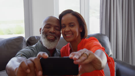 Vista-Frontal-De-Una-Pareja-Negra-Madura-Haciendo-Clic-En-Selfie-Con-Teléfono-Móvil-En-Una-Casa-Cómoda-4k