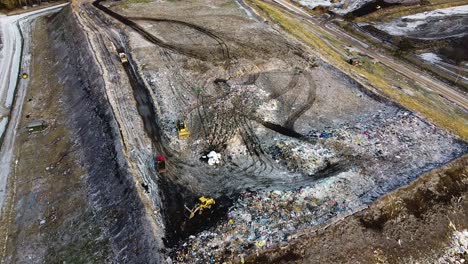 Aerial-flyover-landfill-full-of-trash,-pollution-environmental-problem,-garbage,-trucks-dump-waste-products-polluting-in-a-dump,-wide-angle-drone-shot-moving-backwards