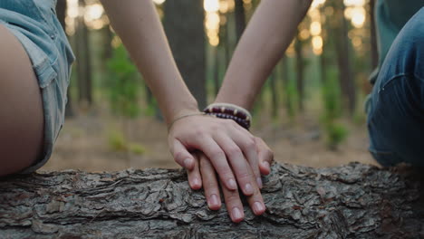 couple-holding-hands-sitting-on-log-in-forest-boyfriend-and-girlfriend-sharing-romantic-connection-in-woods-happy-young-lovers
