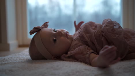 Close-up-of-a-newborn-baby-girl-with-big-dark-eyes-and-dressed-in-pink-for-ceremony