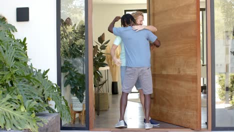 amigos varones felices diversos saludando y abrazando en la puerta principal de la casa, cámara lenta