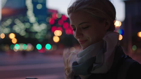 portrait of beautiful young blonde woman texting browsing using smartphone social media app waiting in city street at night enjoying calm evening