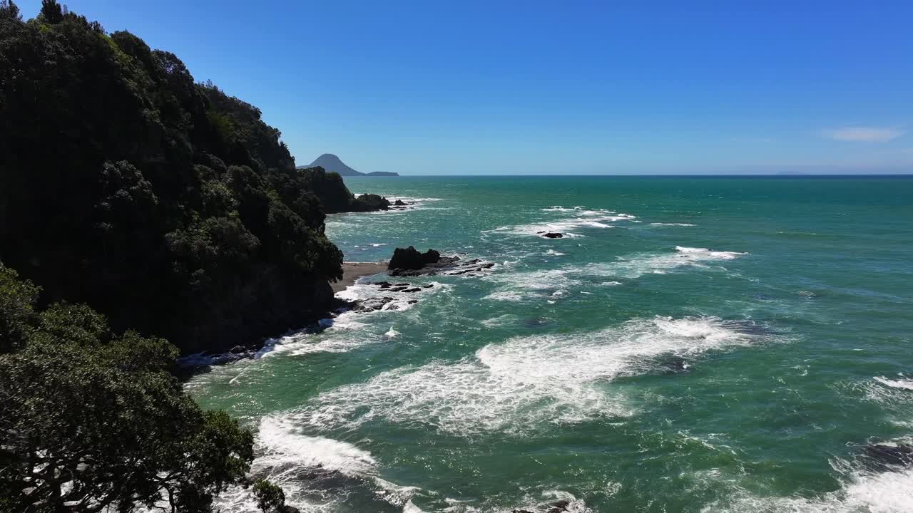 Secret beech Unspoilt jagged coastline—turquoise waves crash against cliffs, windswept trees cling to edges, and sunlight flickers across the wild, untouched shore. Drone New Zealand Whakatane