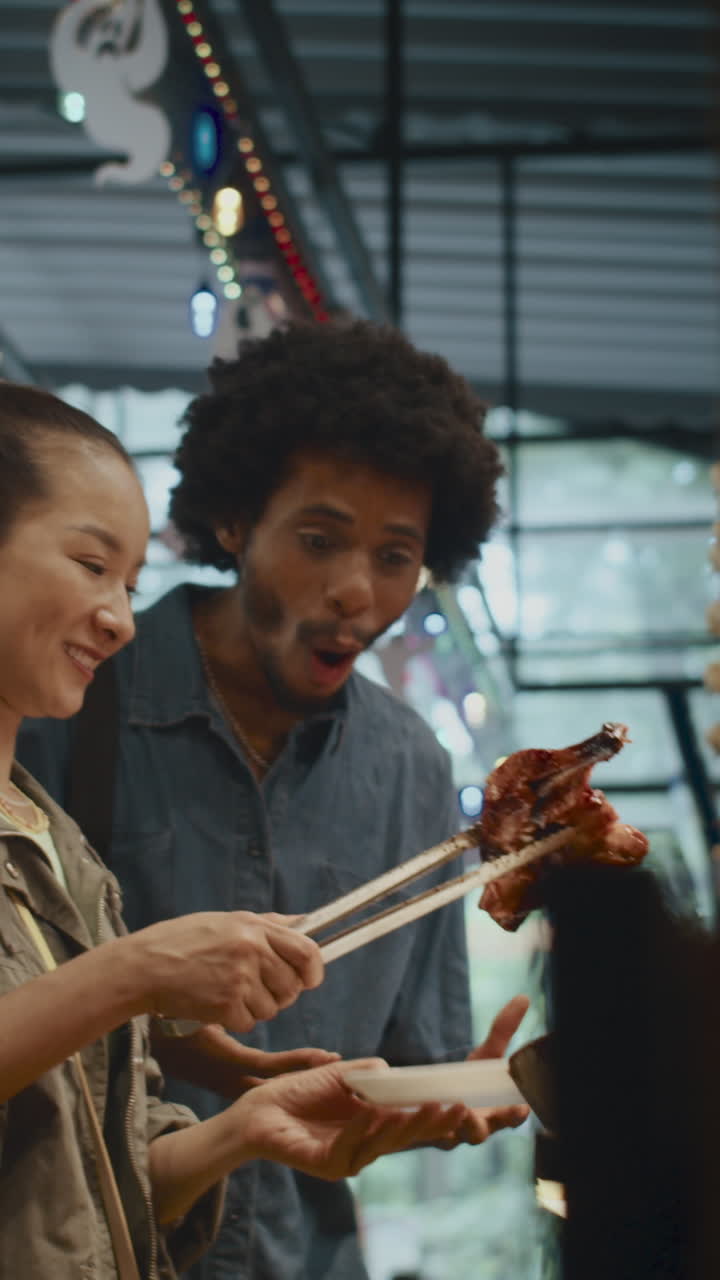 Multiethnic Couple Buying Grilled Chicken for Lunch at Street Food Market