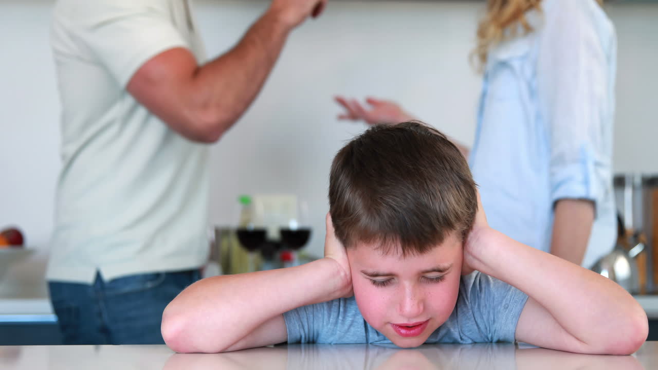 Bambino piccolo che si tappa le orecchie per non sentire i genitori che litigano