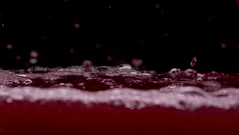 red blood like liquid splashing and bubbles in slow motion in dark tank