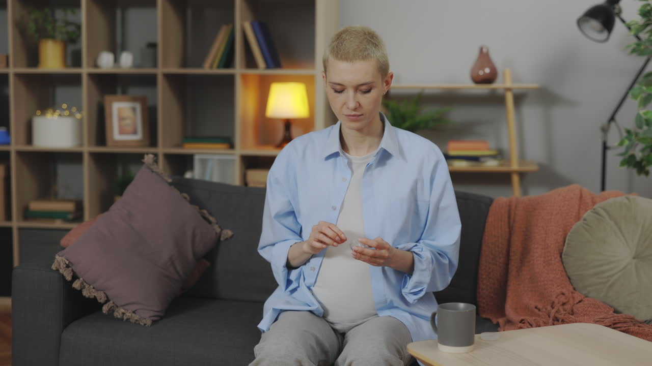 Pregnant woman taking medicine and drinking coffee at home