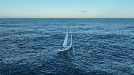 Drone-rotational-shot-of-single-lone-Sailing-Yacht-in-ocean,-at-full-sail