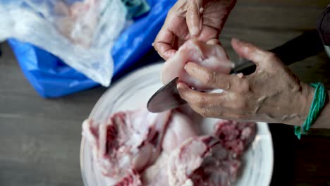 skilled indian chef hands using traditional aruvamanai to cut chicken close-up