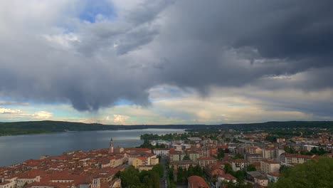 único lapso de tiempo de gran angular de nubes oscuras en movimiento sobre la ciudad de arona y el lago maggiore en italia