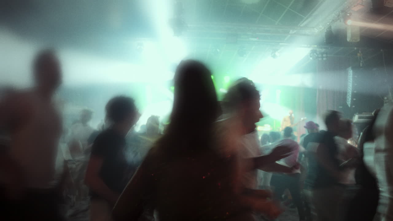 Silhouetted figures dancing in a vibrant atmosphere with colorful lights and energetic ambiance