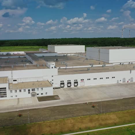 modern manufacture under blue sky. industrial plant among field. new large agriculture buildings. drone side view.