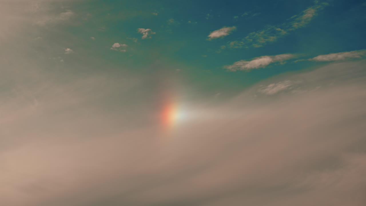 A subtle, soft sky with a faint vertical rainbow or sundog, blending warm and cool tones