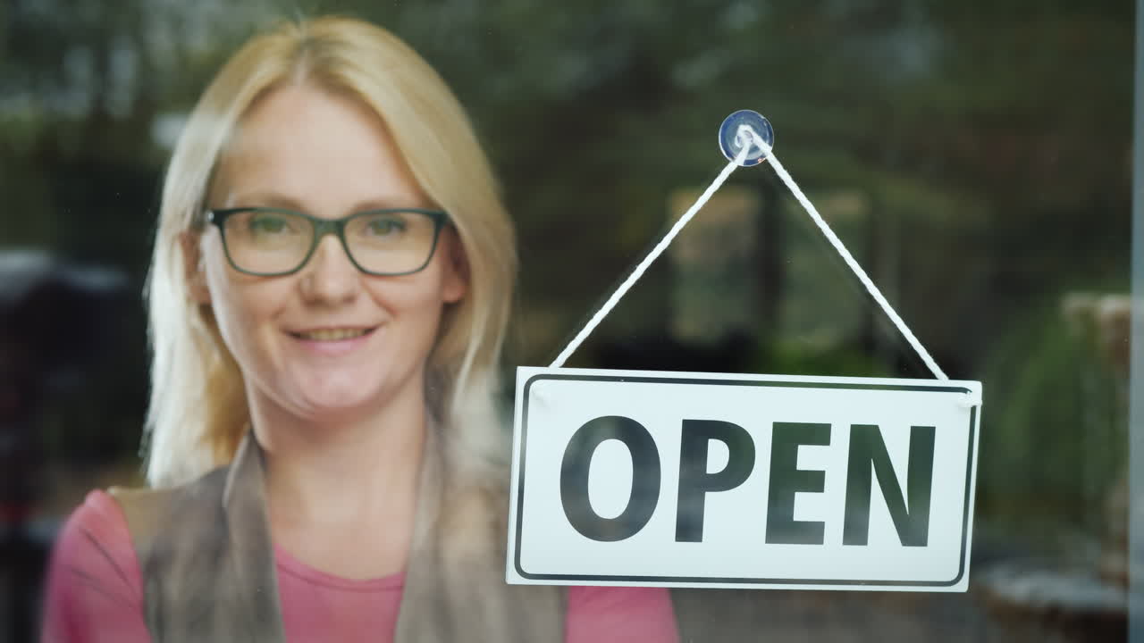 retrato de una mujer exitosa - la propietaria de su negocio parada detrás de la puerta de vidrio en el pla