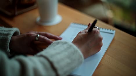 mujer escribiendo en un cuaderno en un café