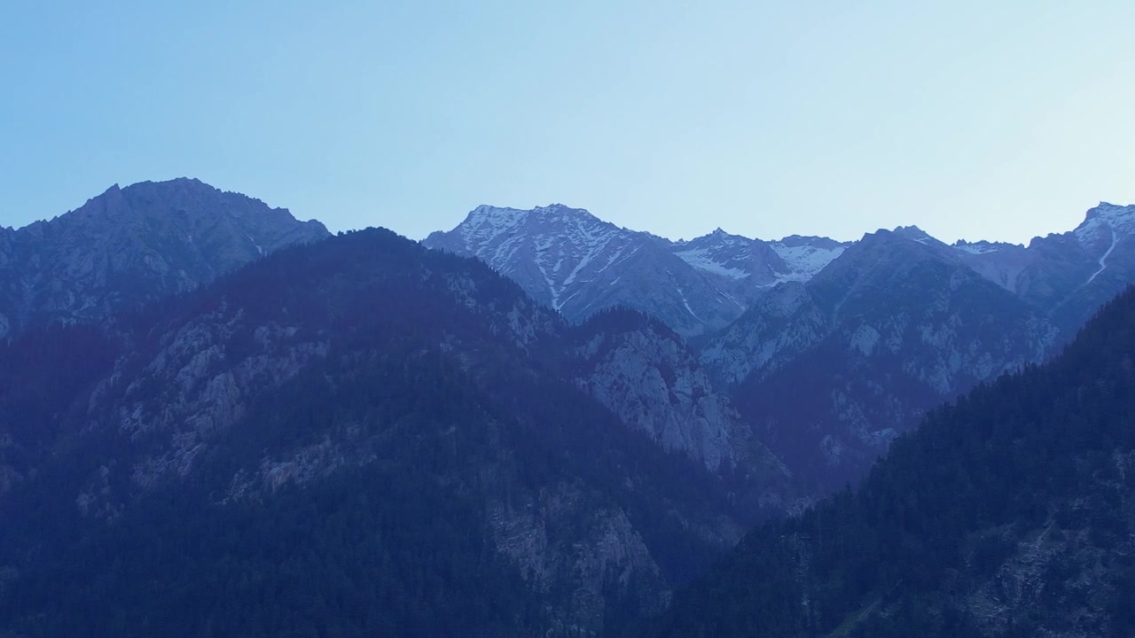 在藍色時分，庫姆拉特崎嶇山脈的寧靜電影感廣角鏡頭，展示了白雪覆蓋的山峰和深邃的山谷陰影。非常適合旅遊紀錄片和自然背景。