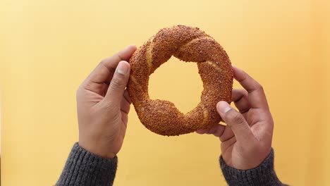 hands holding a turkish bread with sesame seeds