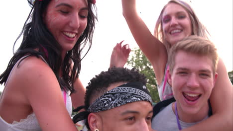 young friends piggy backing at a music festival, close-up