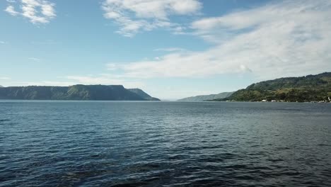 Drone-flying-low-of-the-water-in-Lake-Toba,-Sumatra,-Indonesia