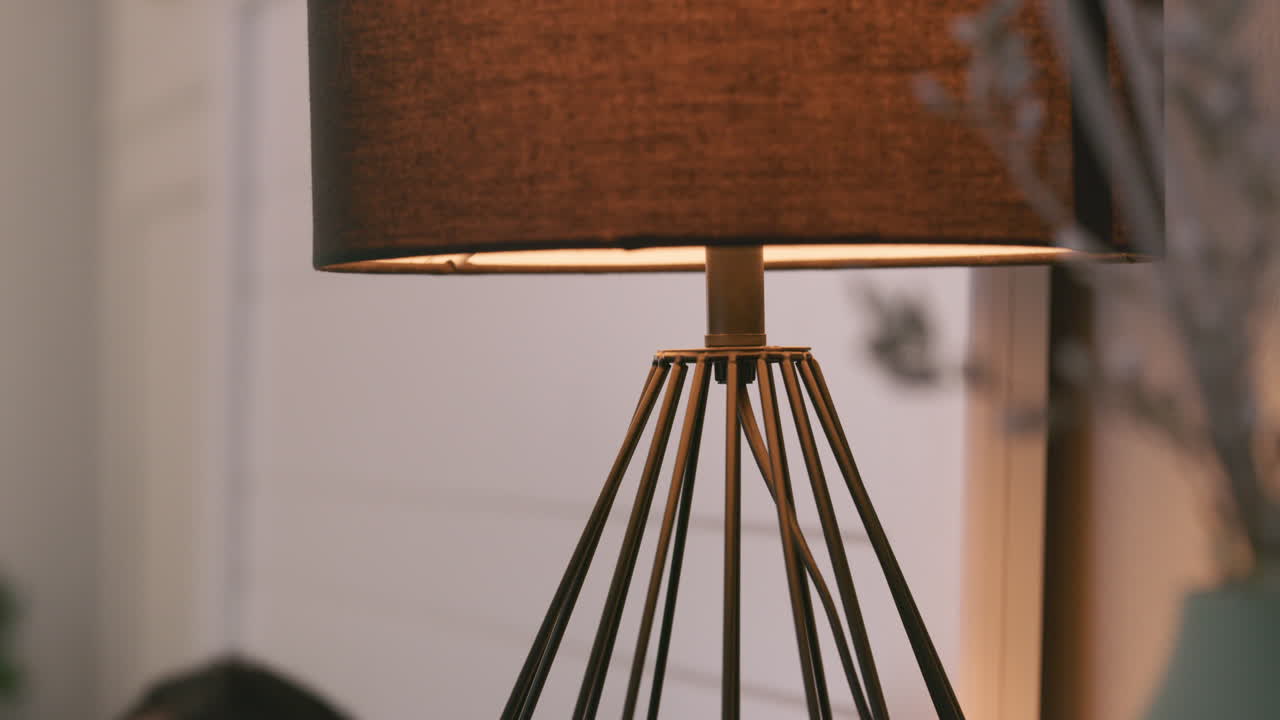 Close-up of a modern table lamp with a person's hand