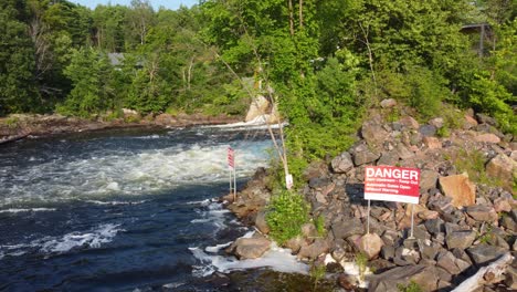 drone flight passes over the water through the outlet of a dam and the warning signs