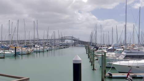 Veleros-Estacionados-Con-El-Puente-Del-Puerto-En-El-Fondo-Visto-En-El-Océano,-Westhaven,-Auckland,-Nueva-Zelanda