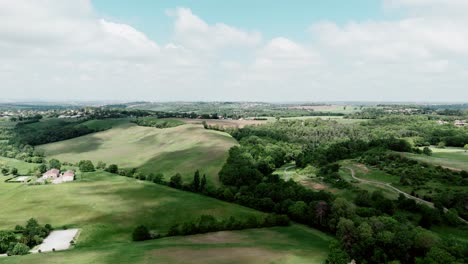 Vista-Aérea-De-Exuberantes-Campos-Verdes-Y-Colinas-Bajo-Un-Cielo-Parcialmente-Nublado-En-Toulouse,-Francia