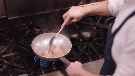 cook stirs with a spoon through a frying pan on the fire in which the meat is cooked