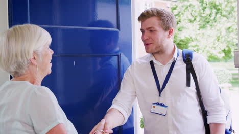 senior woman greeting male care worker making home visit