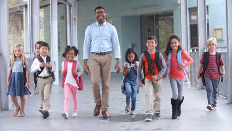 Male-teacher-walking-in-corridor-with-elementary-school-kids