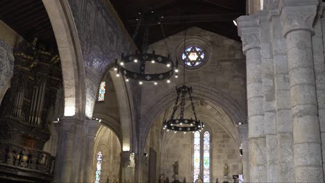 wide shot of portuguese church interior with stone arches stained glass and chandeliers