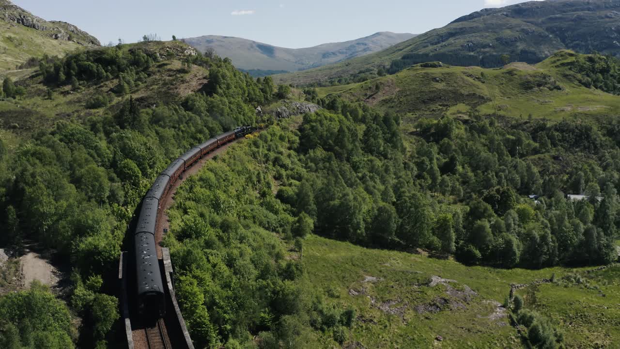 toma de dron del expreso de hogwarts pasando por el campo verde de escocia