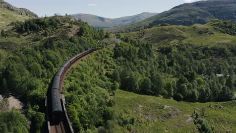 drone shot of the hogwarts express passing through scotland's green countryside