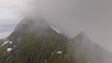 Djevelporten-Noruega-Aérea-V1-Cinemática-Toma-De-La-Naturaleza-Sobrevuelo-De-Drones-Escarpadas-Crestas-Montañosas-Cubiertas-De-Una-Gruesa-Capa-De-Niebla,-La-Panorámica-Revela-El-Hermoso-Paisaje-De-Lofoten---Filmada-Con-Mavic-3-Cine---Junio-De-2022