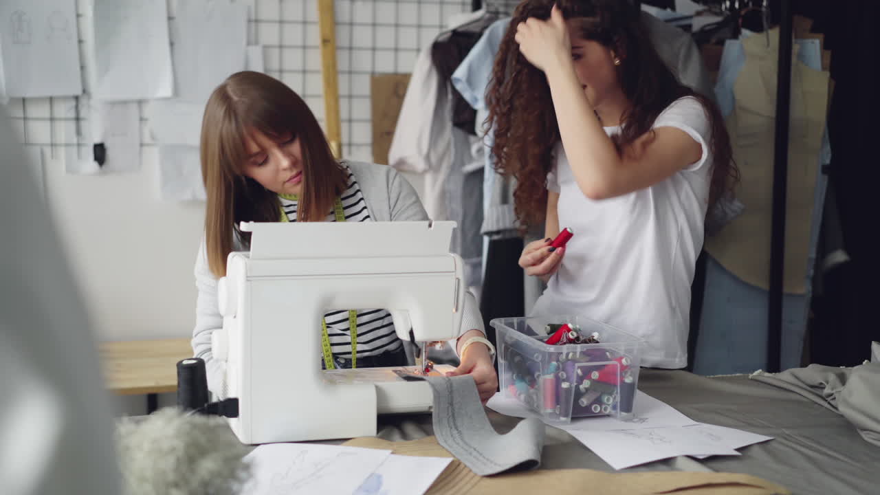 Two women collaborating on a sewing project in a design studio
